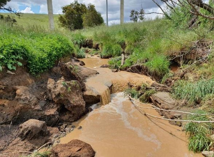 Brown coloured water flowing along a creek.